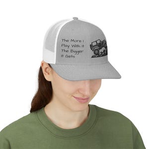 May include: Grey trucker cap with a white mesh back. The cap features the text "The More I Play With It The Bigger It Gets" and a black graphic of a jeep climbing a hill.