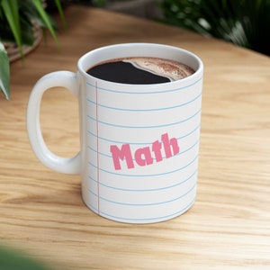May include: White ceramic coffee mug with a blue and white lined design. The word "Math" is written in pink on the mug.