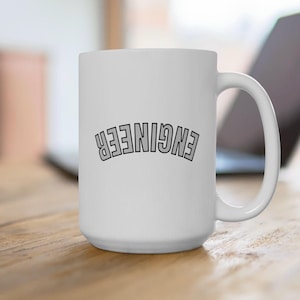 May include: White ceramic coffee mug with the word "ENGINEER" printed in black letters in an arc shape.