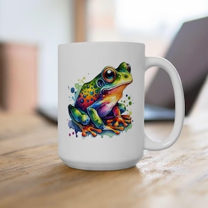 May include: White ceramic mug with a colorful illustration of a frog with green, blue, yellow, and red colors. The frog is sitting on a watercolor background.