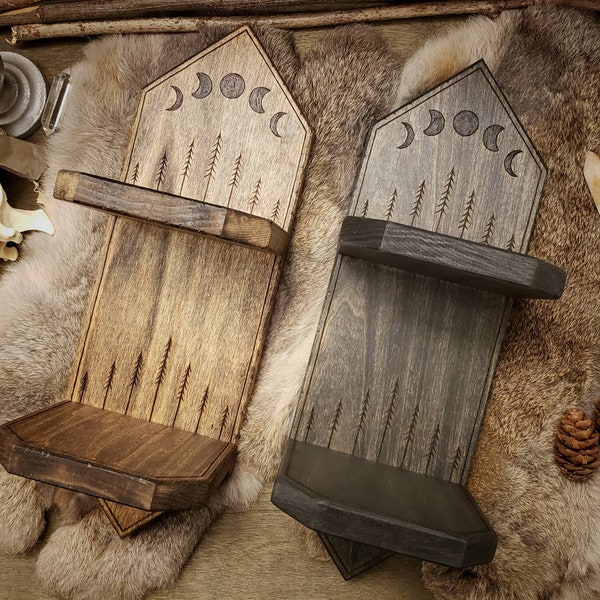 May include: Two wooden wall shelves with a triangular top and a crescent moon design. The shelves are stained in a dark brown and black finish. The shelves have a small ledge on the front.