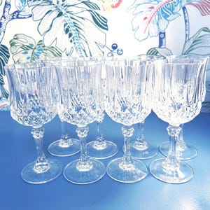 May include: Set of eight clear glass wine glasses with a diamond pattern. The glasses have a tall, slender stem and a wide bowl.