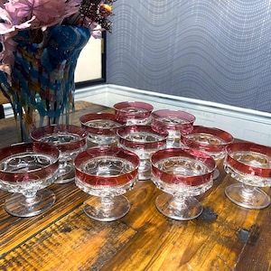 May include: Set of twelve clear glass dessert dishes with a red rim. The dishes have a scalloped edge and a pedestal base.