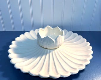 May include: White ceramic serving dish with a scalloped edge and a smaller, separate bowl in the center. The bowl is shaped like a flower bud.