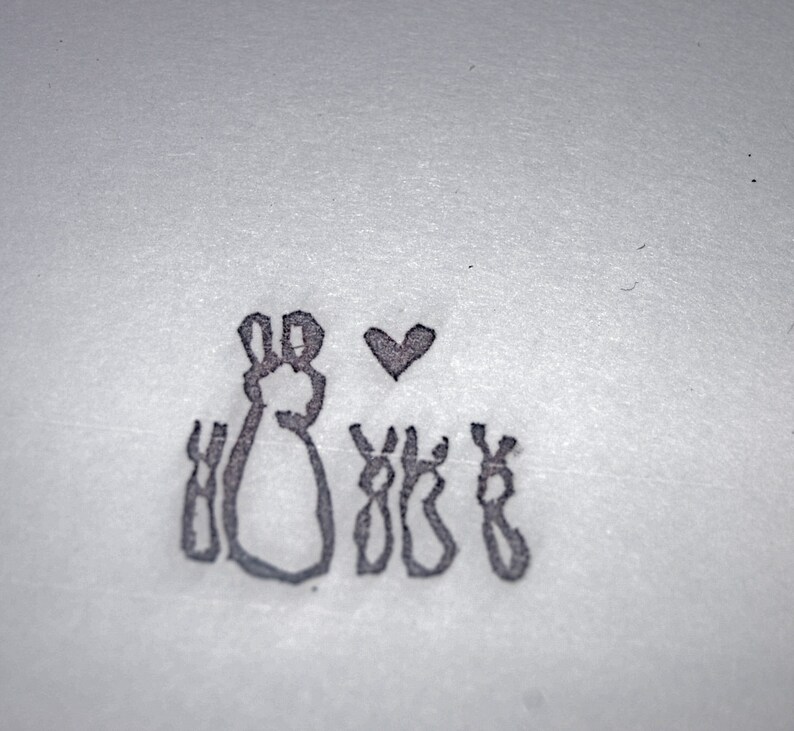 May include: A simple black and white drawing of a rabbit with four smaller rabbits, all facing forward. A small heart is drawn above the larger rabbit.