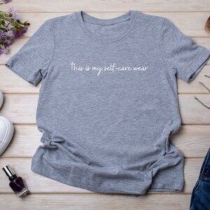 May include: Gray t-shirt with the text "This is my self-care wear" printed in white on the front.