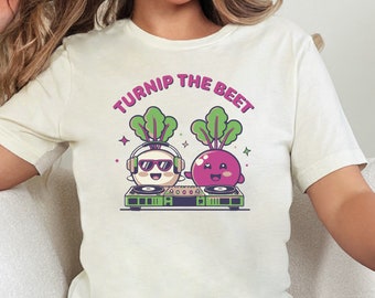 May include: White t-shirt with a graphic of a turnip and a beet wearing headphones and playing a record on a turntable. The text "Turnip the Beet" is written in pink above the graphic.