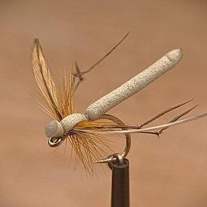 Może przedstawiać: Wabik do połowu muchowego w kolorze brązowym i beżowym z białym korpusem z pianki i długimi, cienkimi skrzydłami.