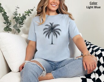 Könnte beinhalten: Ein hellblaues T-Shirt mit einem schwarzen Palmenbaum-Motiv. Das T-Shirt ist aus einem weichen, bequemen Material gefertigt.