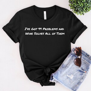Puede incluir: Camiseta negra con texto blanco que dice "Tengo 99 problemas y el vino los resuelve todos".