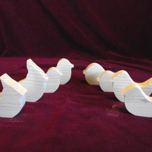 Puede incluir: Un conjunto de siete formas de p&aacute;jaros de madera sin terminar, todas orientadas en la misma direcci&oacute;n. Los p&aacute;jaros est&aacute;n dispuestos en fila, con el p&aacute;jaro m&aacute;s grande en la parte posterior y el p&aacute;jaro m&aacute;s peque&ntilde;o en la parte delantera. Los p&aacute;jaros est&aacute;n hechos de madera de color claro.