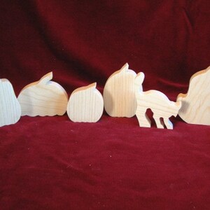 May include: A set of six wooden cutout shapes, including a pear, two apples, a deer, and two other shapes. The shapes are all made of unfinished wood and have a natural wood grain.