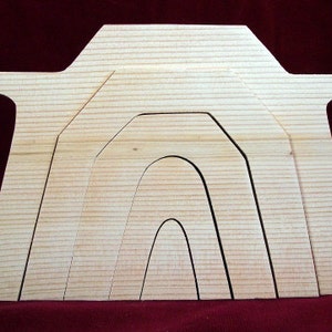May include: A wooden cutout of a house with multiple layers of arches, creating a nested effect. The cutout is made of light wood and has a natural finish.