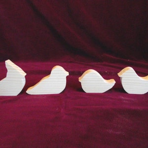 Puede incluir: Cuatro formas de p&aacute;jaros de madera sin terminar, cada una con un dise&ntilde;o diferente. Los p&aacute;jaros est&aacute;n dispuestos en una fila de izquierda a derecha.