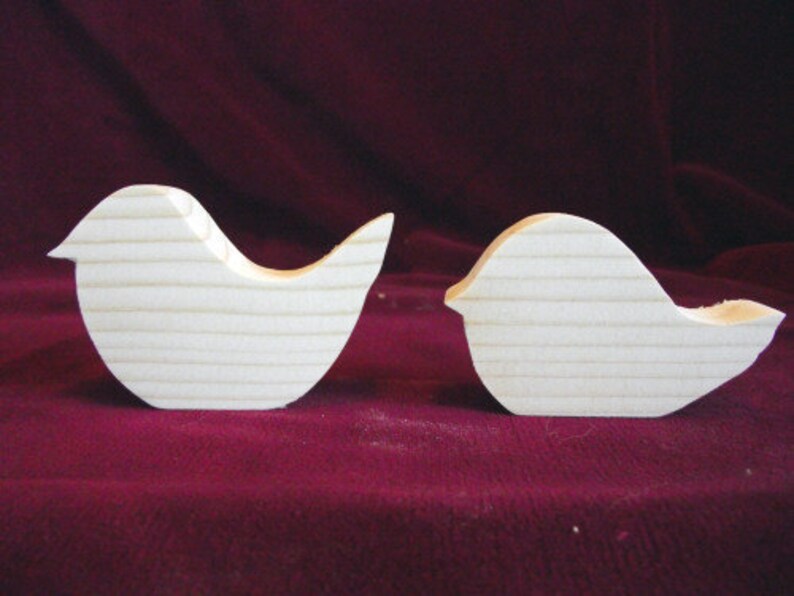Puede incluir: Dos formas de p&aacute;jaros de madera sin terminar. Los p&aacute;jaros son siluetas simples sin detalles. Los p&aacute;jaros est&aacute;n mirando en diferentes direcciones.