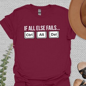 May include: Burgundy t-shirt with the text "IF ALL ELSE FAILS..." and three computer keys labeled "Ctrl", "Alt", and "Del".