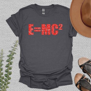 May include: A dark gray t-shirt with a red graphic of the famous equation E=MC2. The equation is made up of various chemical formulas and symbols.