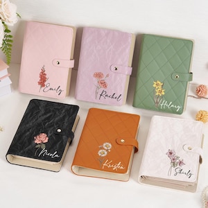 May include: Six personalized journals in various colors: pink, lavender, green, black, orange, and white. Each journal features a floral design and a name in script. The journals have a quilted texture and a snap closure.