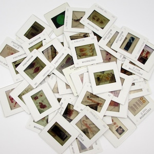 May include: A collection of white square 35mm photographic film slides scattered in a pile. Each slide features a central transparent image, a white plastic frame, and printed text including Brooks/Cole and copyright dates from 2004.
