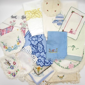 May include: A collection of vintage embroidered linens, including handkerchiefs, doilies, and towels. The items feature floral, butterfly, and geometric designs in various colors, such as blue, yellow, and red. Some pieces have lace edges.