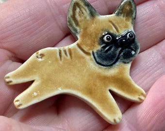 May include: A ceramic figurine of a brown and black French bulldog. The figurine is hand-painted and has a realistic appearance.