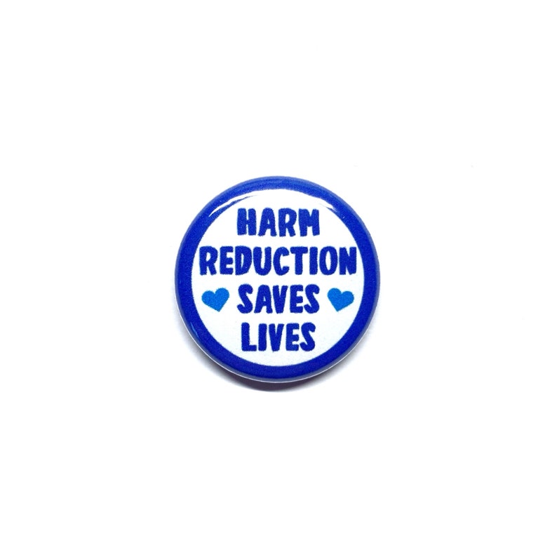Puede incluir: Un bot&oacute;n azul y blanco con el texto "Harm Reduction Saves Lives" y dos corazones azules.