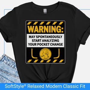 May include: Black t-shirt with a yellow and white graphic that reads "WARNING: MAY SPONTANEOUSLY START ANALYZING YOUR POCKET CHANGE." The graphic includes a quarter coin illustration. The shirt is a SoftStyle® Relaxed Modern Classic Fit.