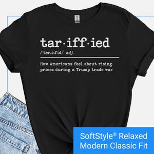 May include: Black t-shirt with white text that reads "tariff-ied /'ter.ə.fıd/ adj. How Americans feel about rising prices during a Trump trade war" and the text "SoftStyle® Relaxed Modern Classic Fit" in blue.