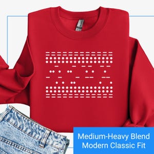 May include: Red sweatshirt with a white design of a Christmas tree made of dots and dashes. The sweatshirt is a medium-heavy blend with a modern classic fit.