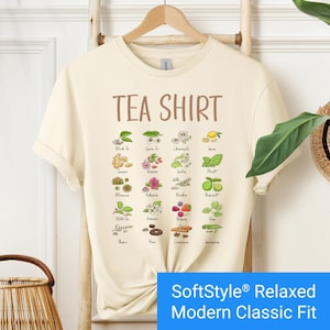 Cream color t-shirt featuring a colorful illustrated grid of tea ingredients like mint, ginger, chamomile, and berries with large text that reads “Tea Shirt” at the top in brown lettering.