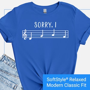 May include: A royal blue t-shirt with white text that reads "SORRY, I" and a musical staff with notes. The t-shirt is a relaxed modern classic fit.