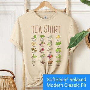Sand color t-shirt featuring a colorful illustrated grid of tea ingredients like mint, ginger, chamomile, and berries with large text that reads “Tea Shirt” at the top in brown lettering.