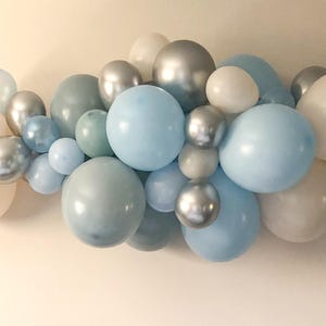 K&ouml;nnte beinhalten: Eine Ansammlung von Ballons in verschiedenen Gr&ouml;&szlig;en und Farbt&ouml;nen von Blau, Silber und Wei&szlig;. Die Ballons sind in einer dekorativen Anordnung angeordnet, passend f&uuml;r eine Party oder Veranstaltung. Die Ballons haben matte und metallische Oberfl&auml;chen.