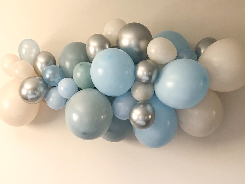 K&ouml;nnte beinhalten: Eine Ansammlung von Ballons in verschiedenen Gr&ouml;&szlig;en und Farbt&ouml;nen von Blau, Silber und Wei&szlig;. Die Ballons sind in einer dekorativen Anordnung angeordnet, passend f&uuml;r eine Party oder Veranstaltung. Die Ballons haben matte und metallische Oberfl&auml;chen.