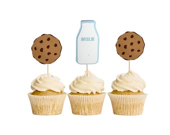 May include: Three cupcakes with white frosting, each topped with a decorative element. Two cupcakes have brown cookie toppers, and one has a light blue milk bottle topper with the word "MILK". The cupcakes sit in beige paper liners.