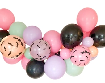 Peut inclure: Un ensemble de ballons colorés dans des tons de rose, noir, pêche, vert et violet. Certains ballons présentent un motif de chauve-souris, idéal pour Halloween ou les fêtes à thème. Les ballons sont disposés en grappe décorative.