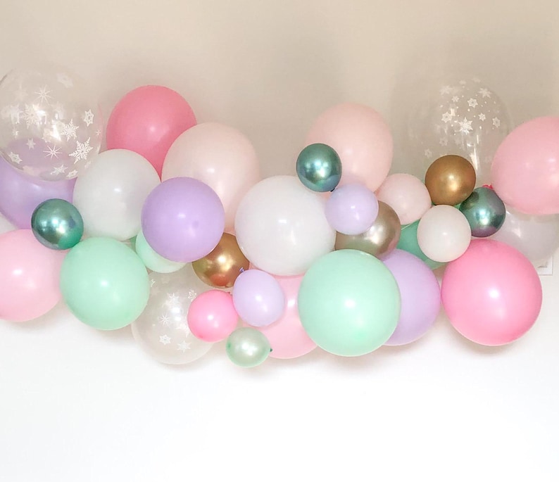 May include: A collection of pastel-colored balloons in pink, mint green, lavender, white, and gold. Some balloons are clear with white star patterns. The balloons vary in size and are clustered together, creating a festive display.