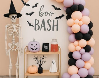 Peut inclure: Décoration d'Halloween avec un squelette portant un chapeau de sorcière, une enseigne « boo BASH » et une arche de ballons pêche, noirs et lavande. Citrouilles décoratives, figurine de fantôme et étagère avec décorations d'Halloween.