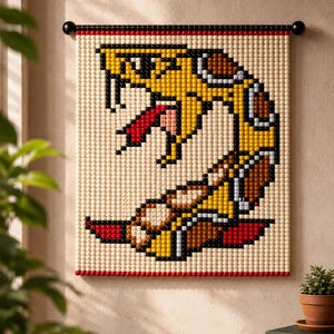 Könnte beinhalten: Ein quadratischer Wandbehang aus kleinen, runden, farbigen Perlen in einem pixeligen Muster. Das Design zeigt eine gelbe Schlange mit braunen Flecken, einer roten Zunge und schwarzen Umrissen, aufgehängt an einer schwarzen Stange mit roten Perlen.