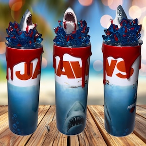May include: Three 20 oz. stainless steel tumblers with a red, white and blue Jaws theme. The tumblers feature a shark fin and a shark head with blood dripping down the side. The tumblers are perfect for any Jaws fan.