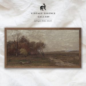 May include: A framed painting depicting a landscape scene with trees and a stream in the foreground. The sky is a muted grey with hints of blue. The trees are a mix of green, brown, and yellow. The stream is a light brown colour. The painting is in a wooden frame.