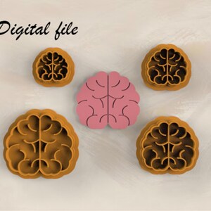 Può includere: Un set di quattro tagliabiscotti marroni a forma di cervello e un pezzo ritagliato rosa a forma di cervello. Il testo Digital file è visibile nell'angolo in alto a sinistra. Gli oggetti sono disposti in gruppo, mostrando il design anatomico.