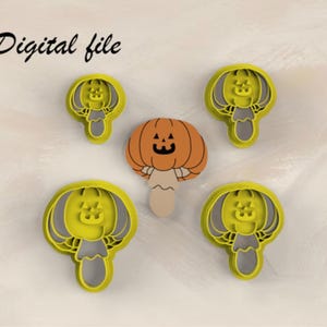 May include: Four yellow plastic cookie cutters shaped like a pumpkin-topped mushroom with a jack-o'-lantern face, surrounding a single orange and beige mushroom-shaped cookie with a jack-o'-lantern face. The text Digital file is visible.