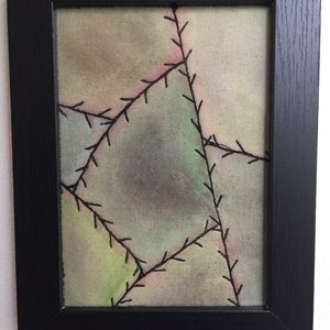 Peut inclure: Une peinture abstraite encadrée avec un motif de patchwork. La toile est peinte dans des tons de vert, rose et marron, et les coutures sont soulignées en noir.