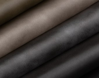 May include: Close-up of four fabric swatches in different shades of brown and gray. The fabric has a textured, slightly pebbled surface.