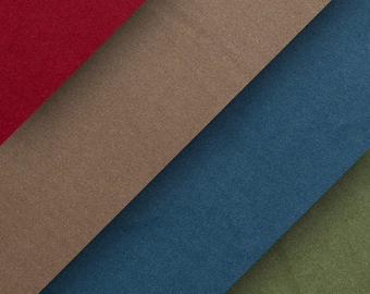 Op de afbeelding: Vier stofstalen in verschillende kleuren en texturen. De stalen zijn diagonaal gerangschikt, met de rode staal linksboven, de bruine staal in het midden, de blauwe staal rechtsonder en de groene staal linksonder.