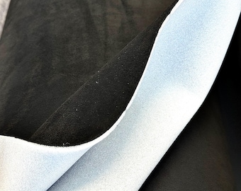 May include: Close-up of a dark gray sheet of fabric with a light blue underside. The fabric is folded over, revealing the contrasting textures and colors. The material appears soft and pliable.