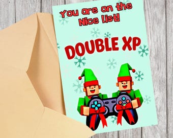 May include: A Christmas greeting card with a light blue background, snowflakes, and the text "You are on the Nice List!" and "DOUBLE XP" in red. Two elf characters hold a game controller with red bows. The card is inside a tan envelope.