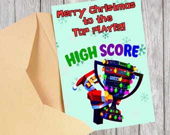 May include: A Christmas card with a light blue background and the text "Merry Christmas to the Top Player!" and "HIGH SCORE". The card features a trophy decorated with Christmas lights and a Santa Claus figure.