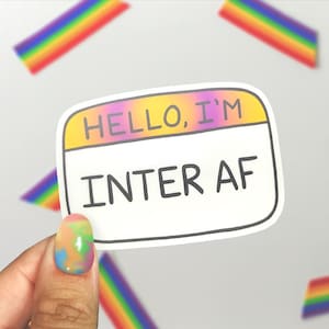 May include: A sticker with a rainbow gradient background and white outline. The sticker says "HELLO, I'M INTER AF" in black text.